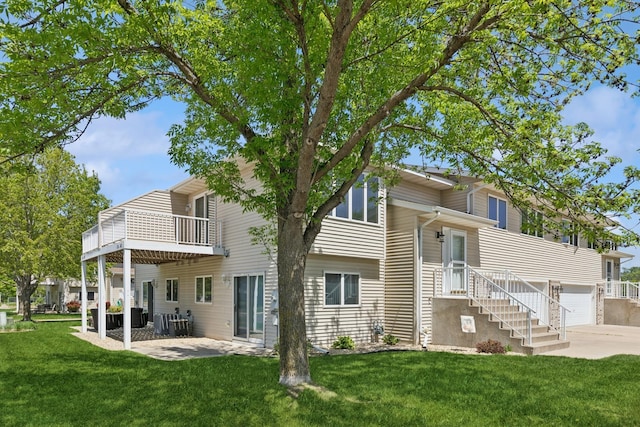 rear view of property featuring driveway, a yard, a balcony, and central AC