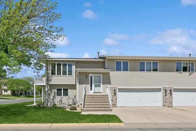 bi-level home featuring concrete driveway, a garage, a front yard, and brick siding
