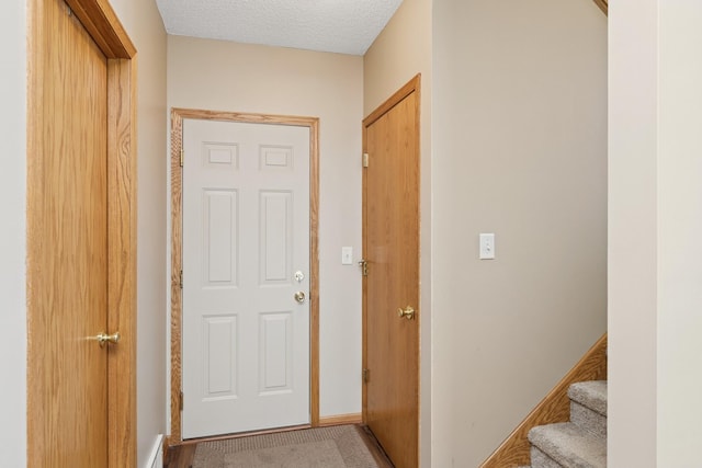hall featuring a textured ceiling, baseboards, and stairway