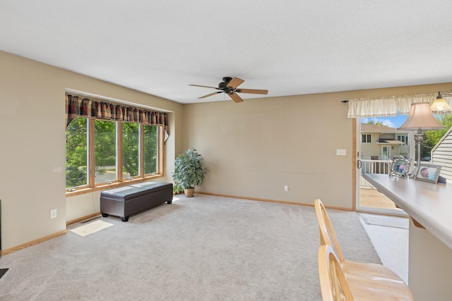 unfurnished living room with a ceiling fan, healthy amount of natural light, carpet, and baseboards