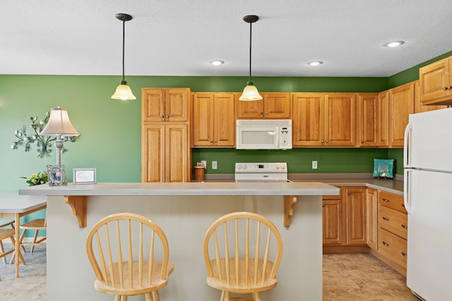 kitchen featuring white appliances, light countertops, a breakfast bar area, recessed lighting, and decorative light fixtures