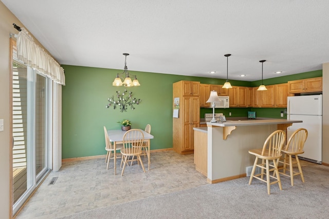 kitchen with white appliances, a kitchen breakfast bar, light countertops, a chandelier, and recessed lighting