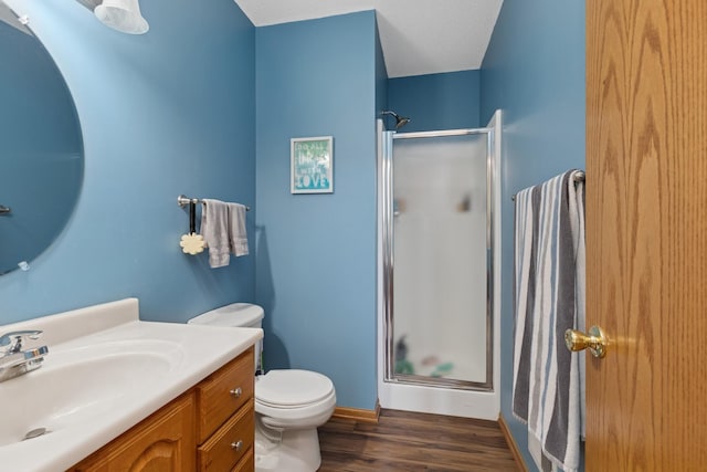bathroom featuring a stall shower, wood finished floors, vanity, toilet, and baseboards