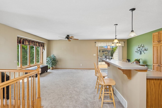 kitchen with healthy amount of natural light, a breakfast bar, ceiling fan, and light countertops
