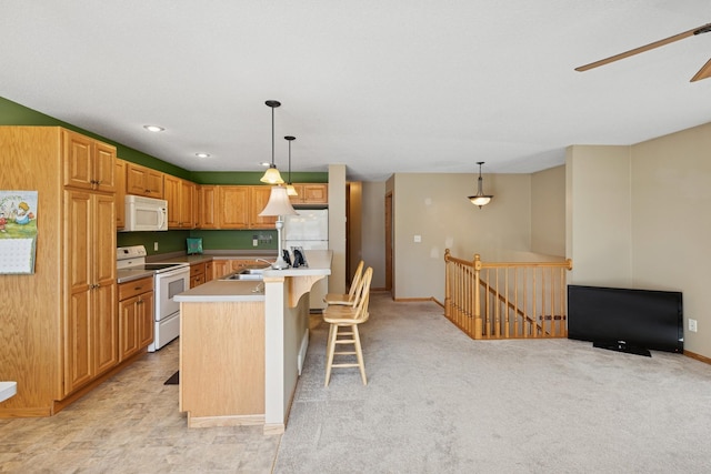 kitchen featuring white appliances, a sink, pendant lighting, light countertops, and an island with sink