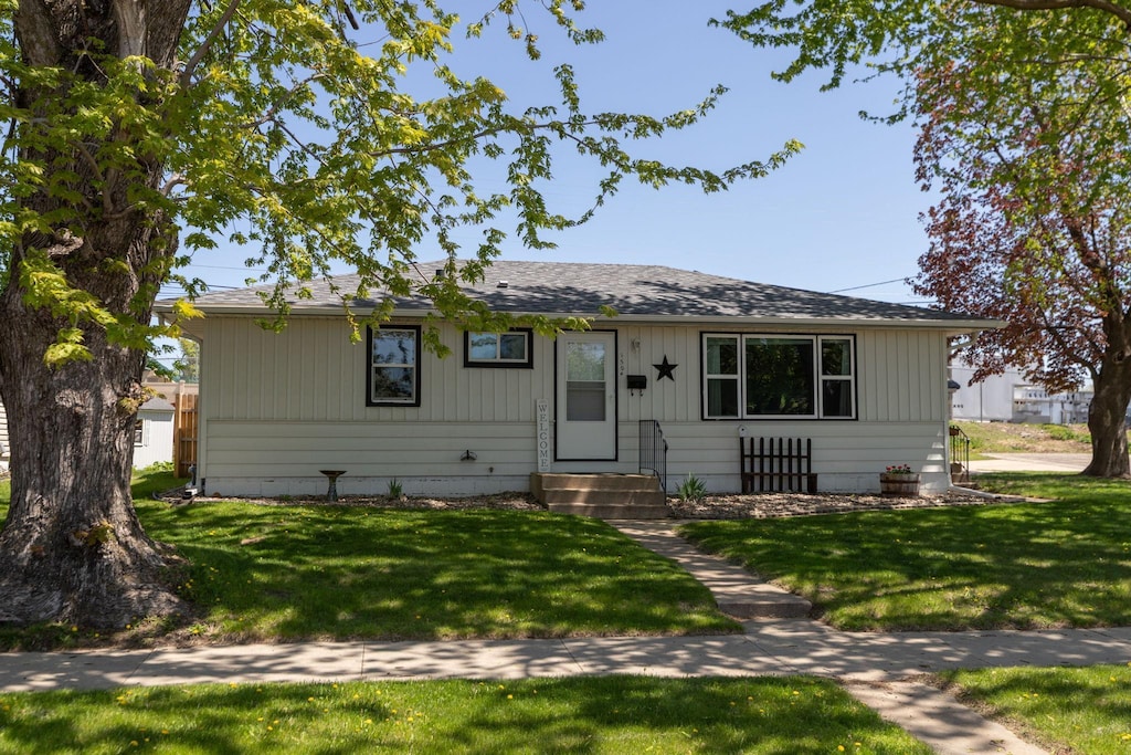 view of front facade featuring entry steps, a front lawn, and roof with shingles