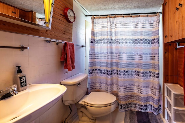 23711 Clarissa Haven Dr, Girard Twp, MN 56551 - bathroom featuring a sink, toilet, a textured ceiling, tile walls, and a shower with shower curtain