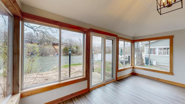 unfurnished sunroom featuring a water view, baseboards, and wood finished floors