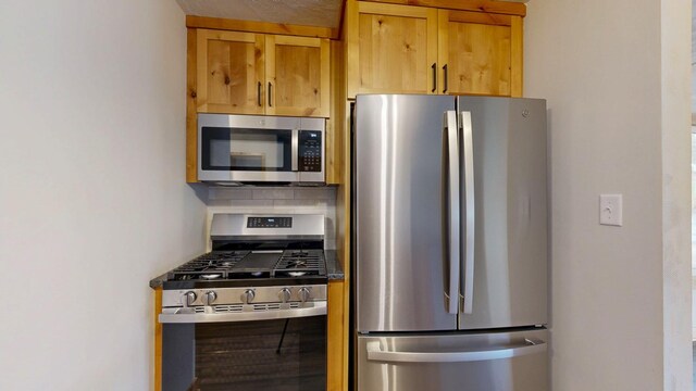 kitchen with appliances with stainless steel finishes, backsplash, and brown cabinetry