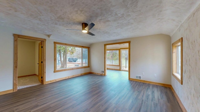 empty room with wood finished floors, baseboards, a ceiling fan, and a textured ceiling
