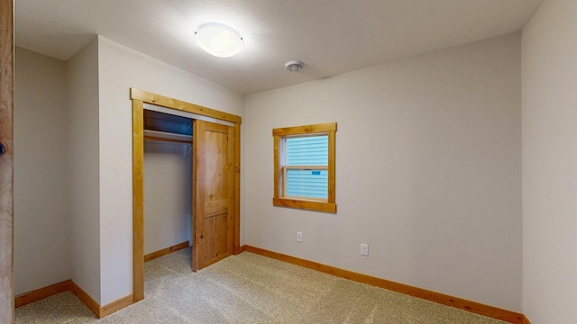 unfurnished bedroom with baseboards, light carpet, and a closet