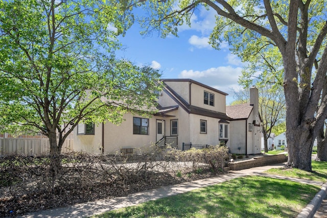 traditional-style home featuring fence, stucco siding, and a chimney