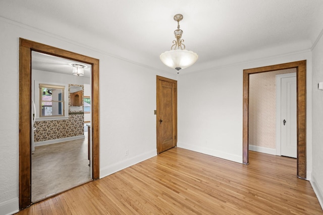 spare room with light wood-style floors, baseboards, and ornamental molding