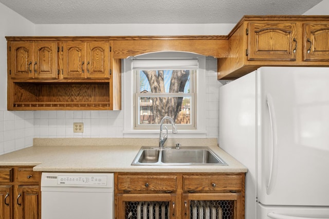 kitchen featuring white appliances, a sink, light countertops, brown cabinets, and backsplash