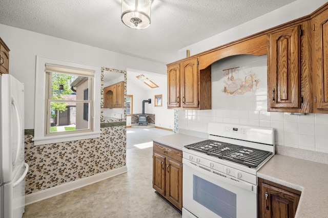 kitchen with white appliances, a wood stove, light countertops, backsplash, and a textured ceiling