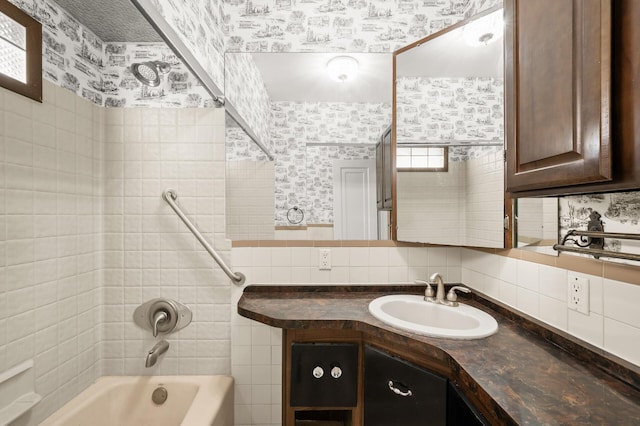 full bath featuring washtub / shower combination, decorative backsplash, wallpapered walls, and vanity