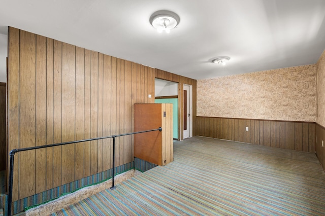 carpeted empty room with wood walls and a wainscoted wall
