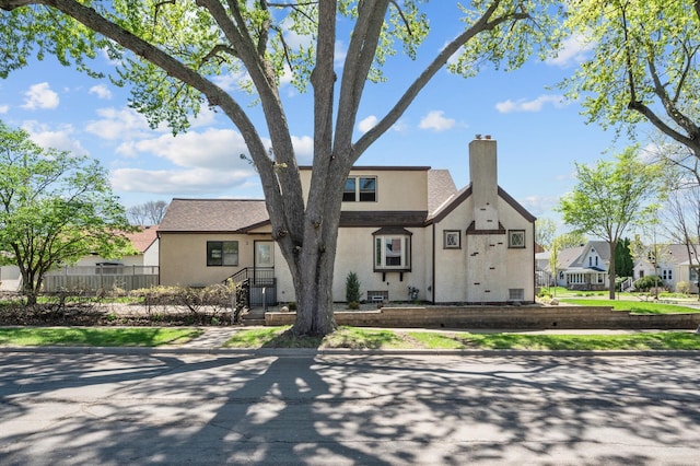 view of front of home with stucco siding, a chimney, fence, and a residential view
