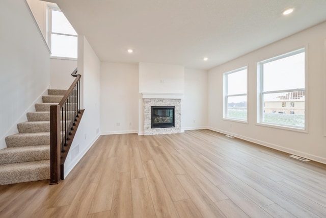 unfurnished living room featuring light wood-style floors, visible vents, and stairway