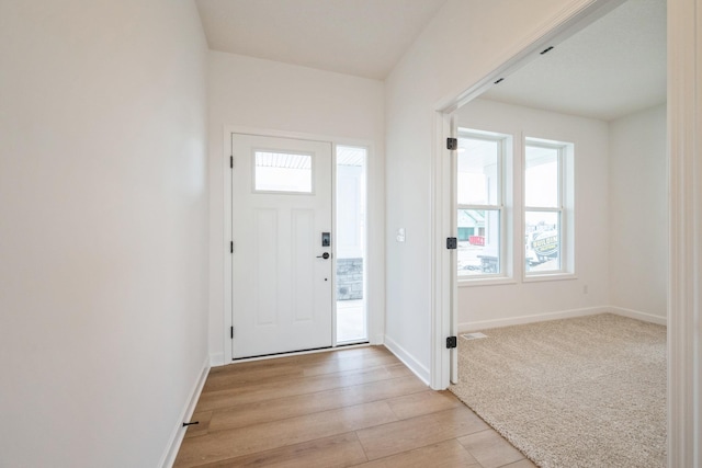 foyer with light wood finished floors, baseboards, and a healthy amount of sunlight