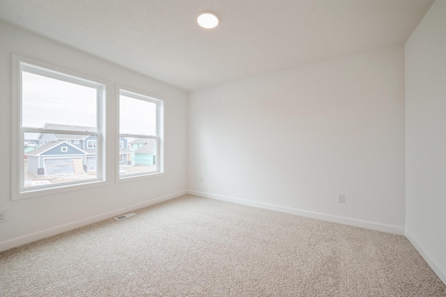 carpeted spare room with baseboards and visible vents