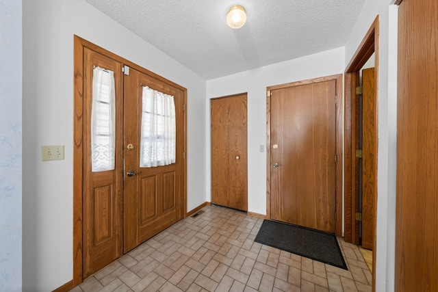 38546 Grand Ave, North Branch, MN 55056 - entryway featuring a textured ceiling, baseboards, and brick patterned floors