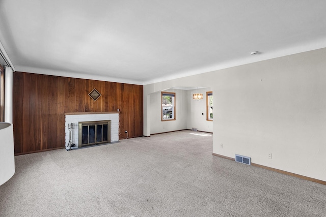 unfurnished living room with wooden walls, carpet floors, a fireplace, and baseboards