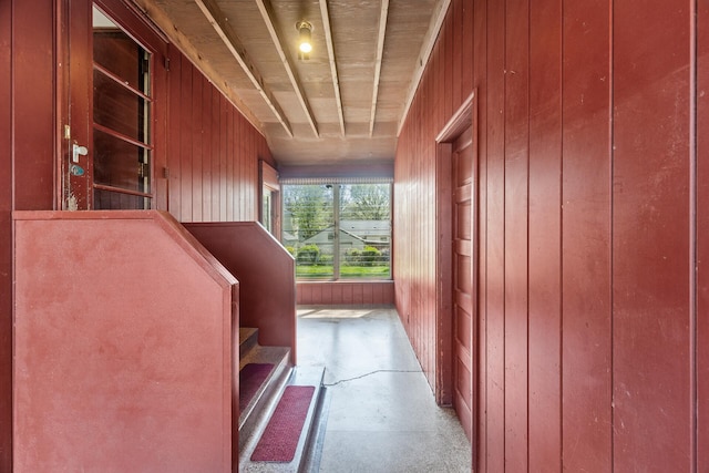 hall featuring concrete flooring and wooden walls