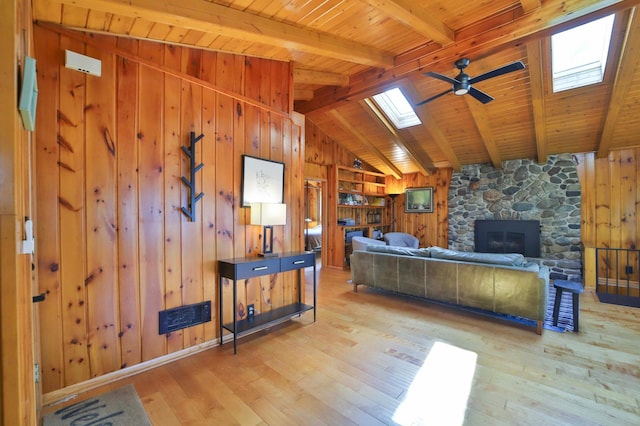 living area featuring a skylight, a ceiling fan, wood-type flooring, wooden ceiling, and wood walls