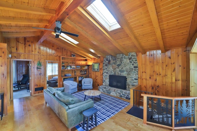 living room featuring a skylight, wood finished floors, wood walls, a stone fireplace, and wooden ceiling