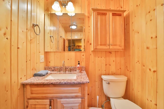 half bathroom with wooden walls, toilet, and vanity
