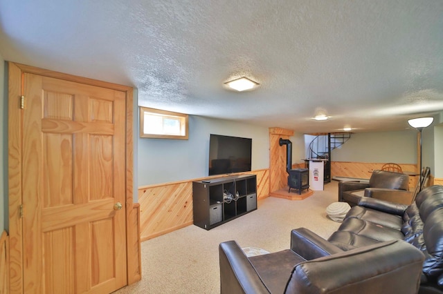 living room featuring wood walls, a textured ceiling, carpet floors, and a wainscoted wall