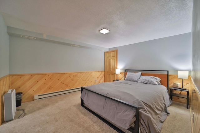 carpeted bedroom with a baseboard radiator, wooden walls, wainscoting, and a textured ceiling