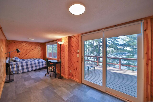 bedroom with wood walls, access to exterior, and tile patterned floors