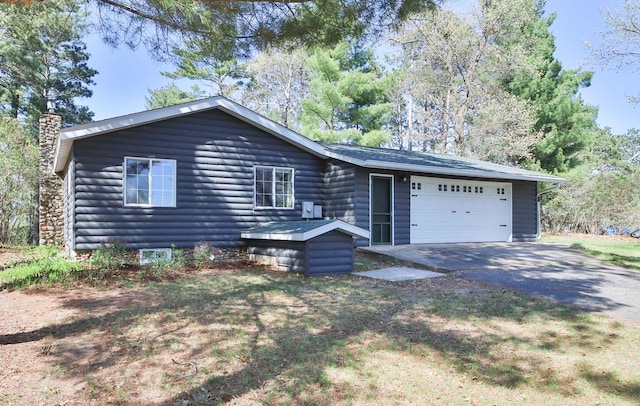 view of front of house with a chimney, asphalt driveway, and a garage