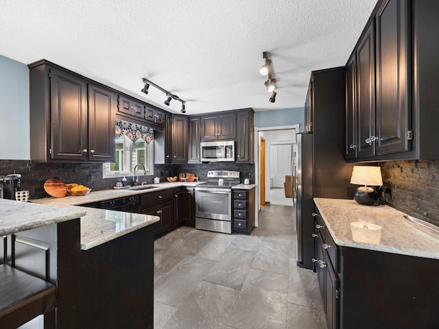 12576 Ridgewood Dr NW, Elk River, MN 55330 - kitchen featuring stainless steel appliances, a sink, rail lighting, backsplash, and a textured ceiling