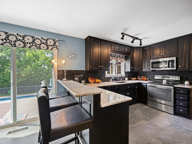 12576 Ridgewood Dr NW, Elk River, MN 55330 - kitchen with appliances with stainless steel finishes, healthy amount of natural light, a textured ceiling, a sink, and a peninsula
