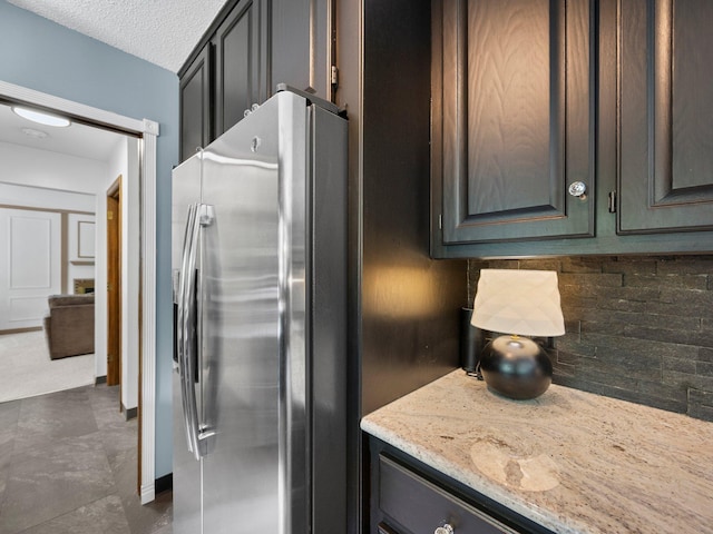 12576 Ridgewood Dr NW, Elk River, MN 55330 - kitchen with stainless steel fridge, decorative backsplash, light stone countertops, and a textured ceiling