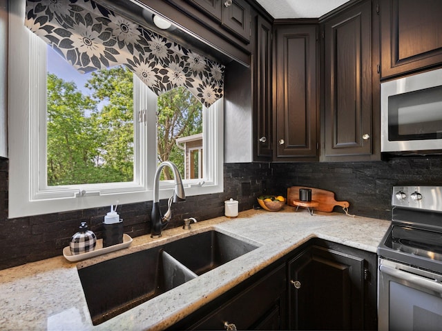 12576 Ridgewood Dr NW, Elk River, MN 55330 - kitchen featuring appliances with stainless steel finishes, a sink, backsplash, light stone counters, and dark brown cabinetry