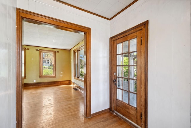 doorway featuring wood finished floors, baseboards, and ornamental molding