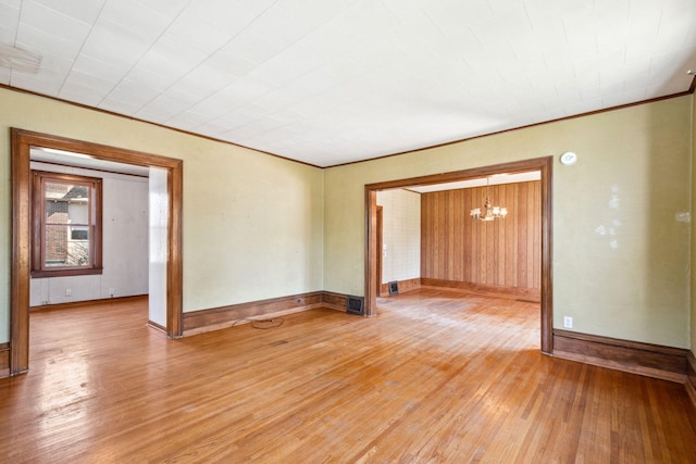 unfurnished room featuring light wood finished floors, a chandelier, baseboards, and ornamental molding