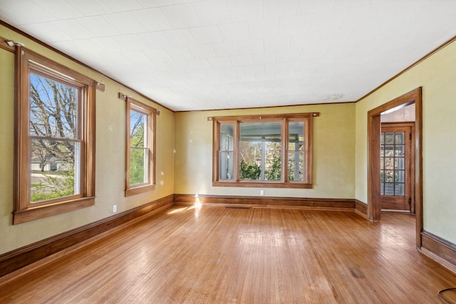 spare room featuring light wood finished floors, baseboards, healthy amount of natural light, and ornamental molding