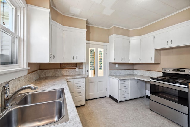 kitchen with stainless steel electric range, a sink, light countertops, ornamental molding, and white cabinetry