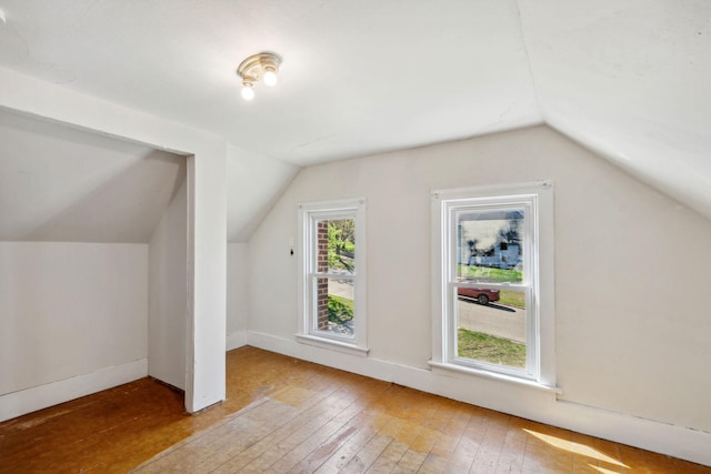 bonus room featuring lofted ceiling, hardwood / wood-style floors, and baseboards
