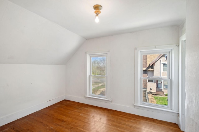 additional living space featuring wood finished floors, lofted ceiling, and baseboards