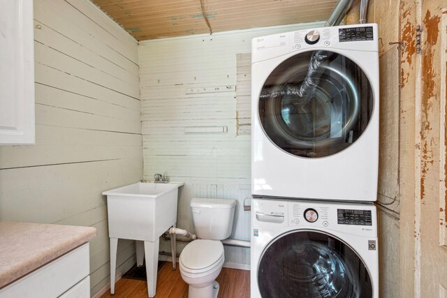 laundry area with stacked washing machine and dryer, wood walls, wood finished floors, and wood ceiling