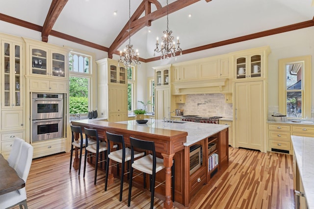 1721 Mount Curve Ave, Minneapolis, MN 55403 - kitchen with cream cabinetry, appliances with stainless steel finishes, a chandelier, tasteful backsplash, and light wood-style floors
