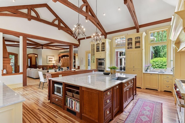 1721 Mount Curve Ave, Minneapolis, MN 55403 - kitchen featuring a sink, stainless steel double oven, light stone countertops, light wood-type flooring, and high vaulted ceiling