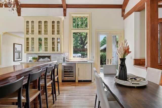1721 Mount Curve Ave, Minneapolis, MN 55403 - kitchen featuring beverage cooler, cream cabinetry, light wood-style floors, decorative backsplash, and ornamental molding
