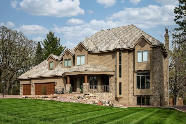 view of front of property with a front yard, covered porch, an attached garage, a chimney, and brick siding
